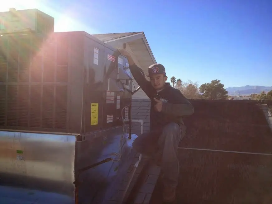 HVAC technician performing AC Tune-Up on a rooftop unit in Ripley